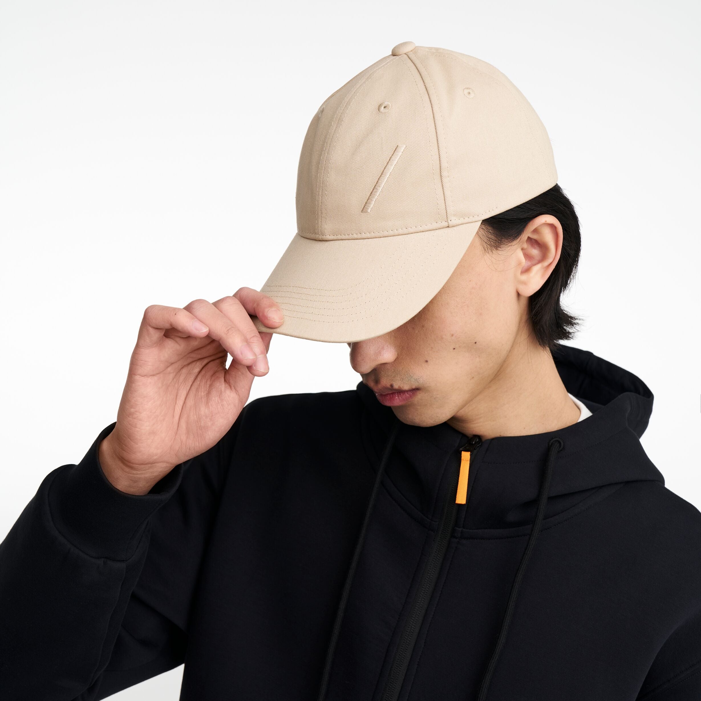 The Volvo Classic Cap in dune, worn by a male model. It features an embroidered diagonal logo on the side. 