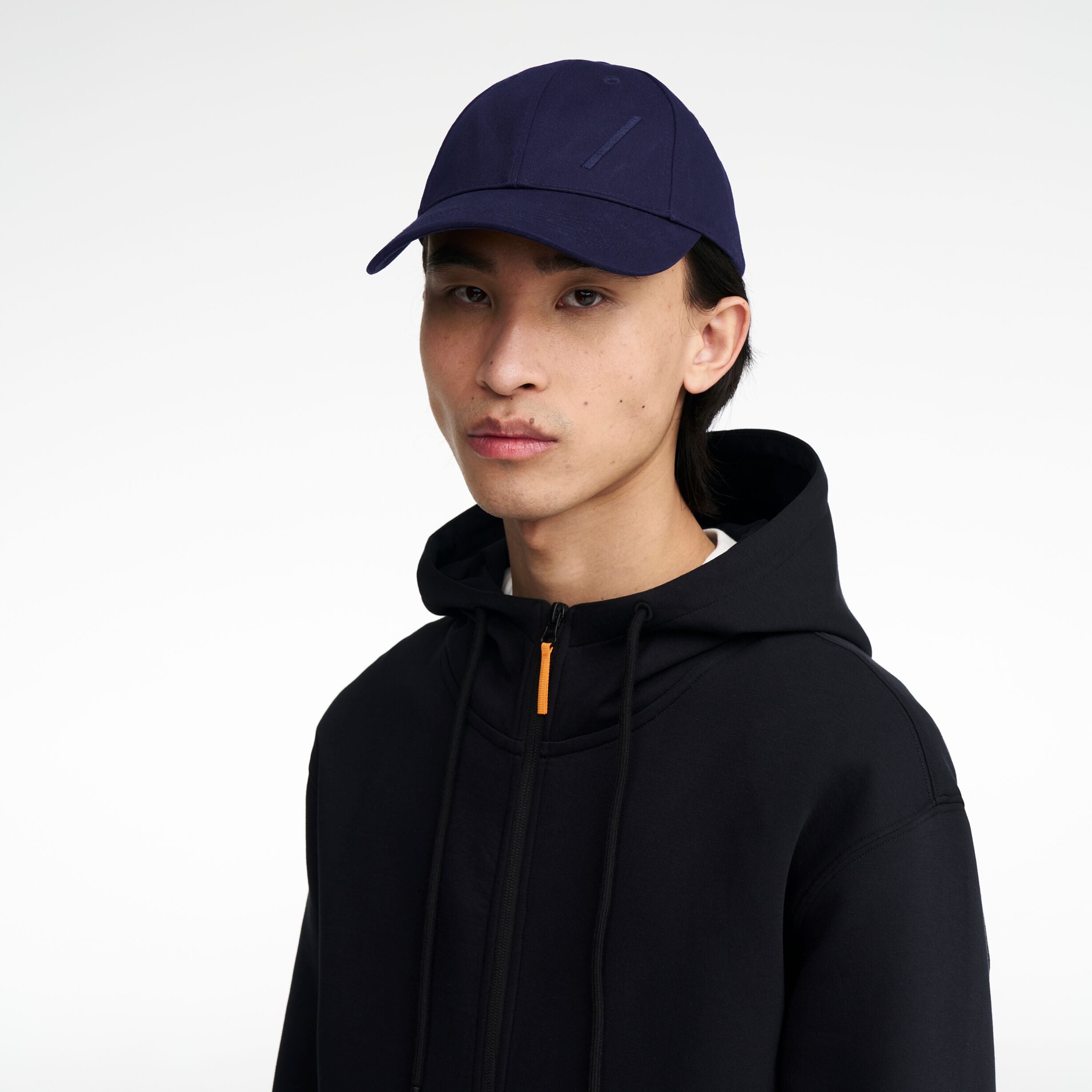 The Volvo Classic Cap in navy, worn by a male model. It features an embroidered diagonal logo on the side. 