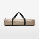 The Volvo Canopy in zipped storage bag against a white background. The taupe coloured bag and white Volvo logo are visible, as well as the large handles for easy carrying.