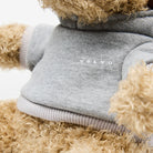 A close-up view of the Volvo Elk Soft Toy. We see the furry face, arms and legs, and the detail on the grey hoodie with white Volvo logo.