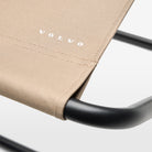 A close-up view of the Folding Stool. Taupe-coloured fabric features the Volvo logo, while a sturdy steel frame holds up to 150 kg.