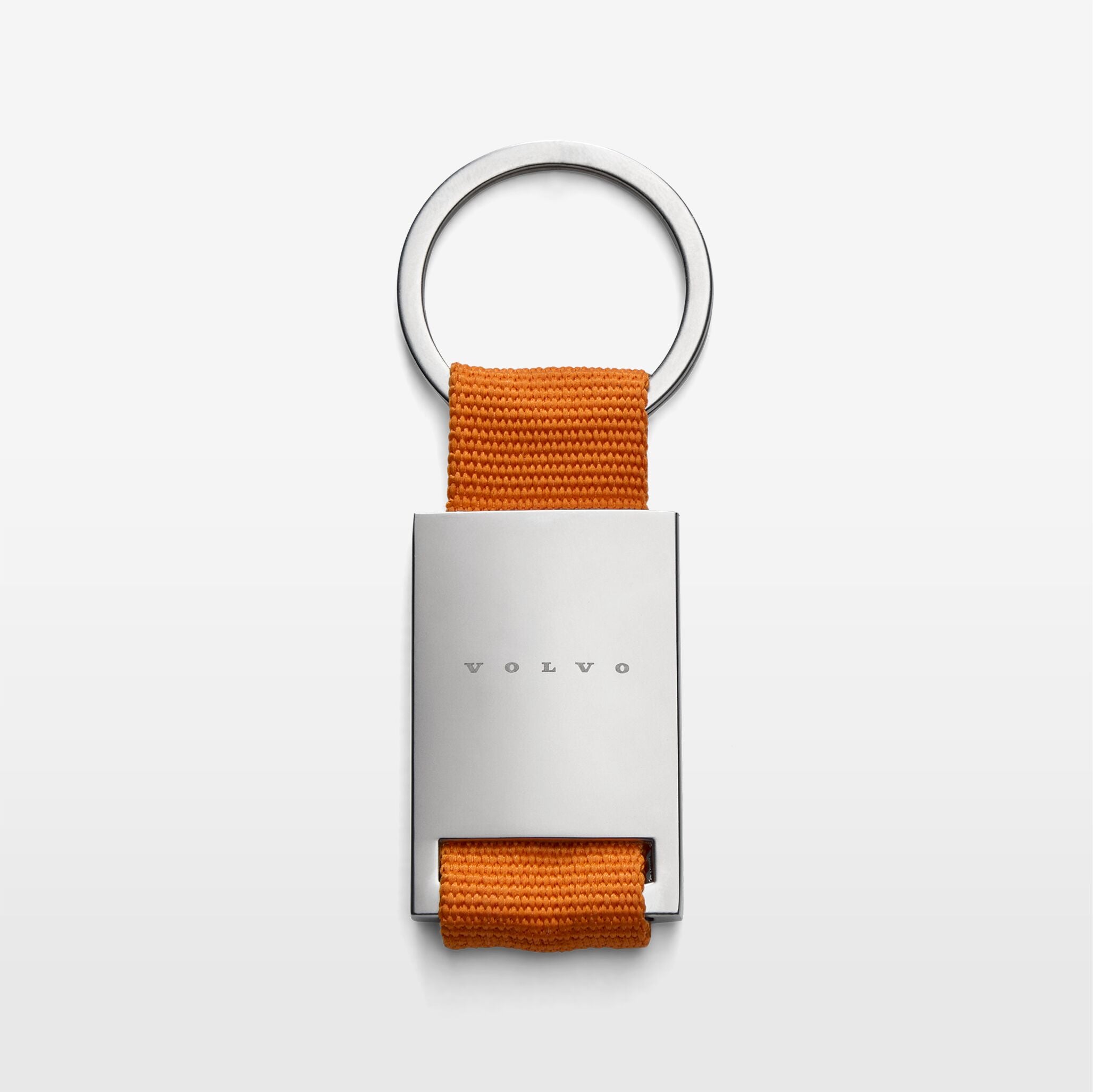 The Volvo Key Chain in orange against a white background. We see the solid metal with Volvo logo at the centre, with strap and key ring at the top.