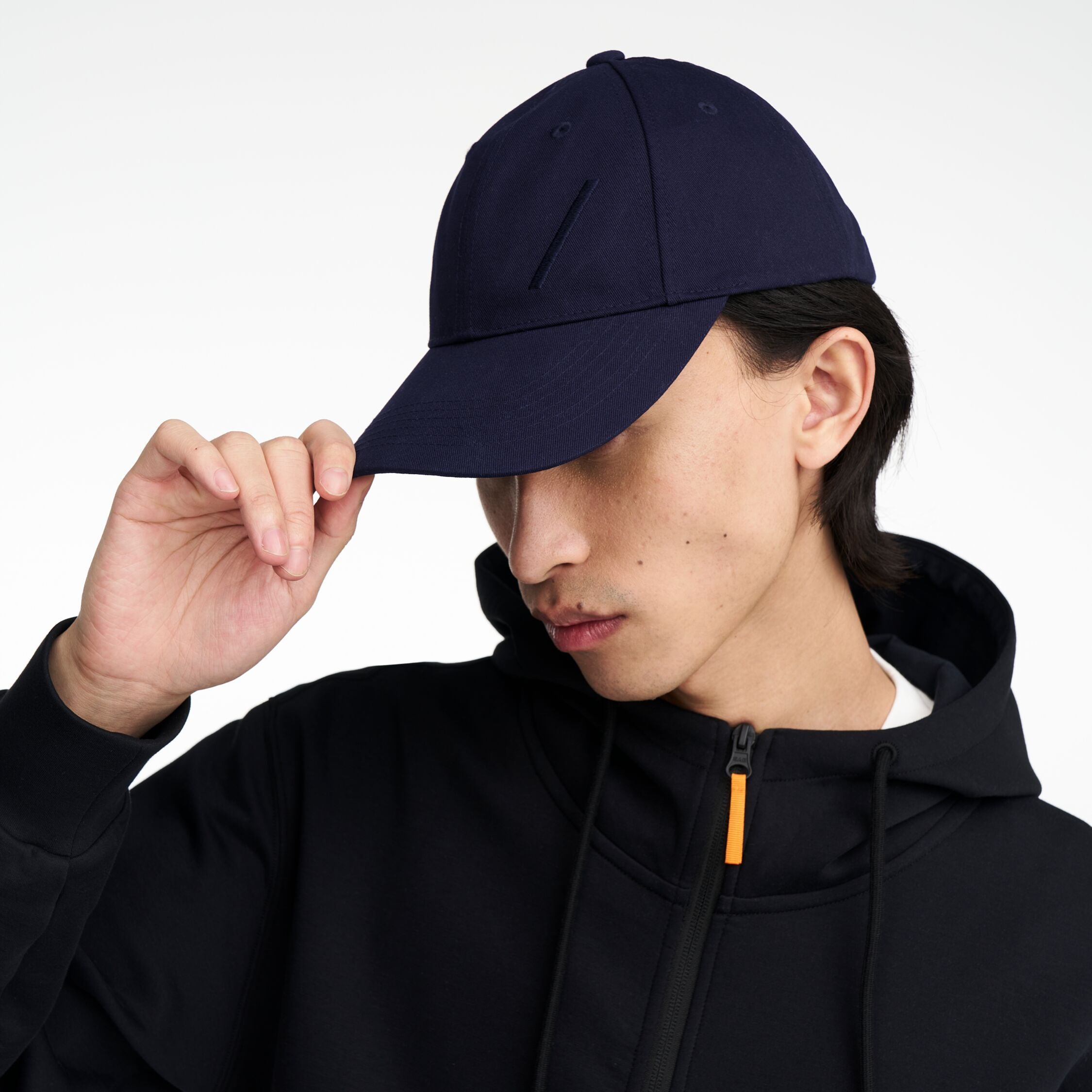 The Volvo Classic Cap in navy, worn by a male model. It features an embroidered diagonal logo on the side. 