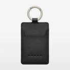 A black textured card holder with a silver metal key ring, featuring the embossed Volvo logo near the bottom, set against a light gray background.