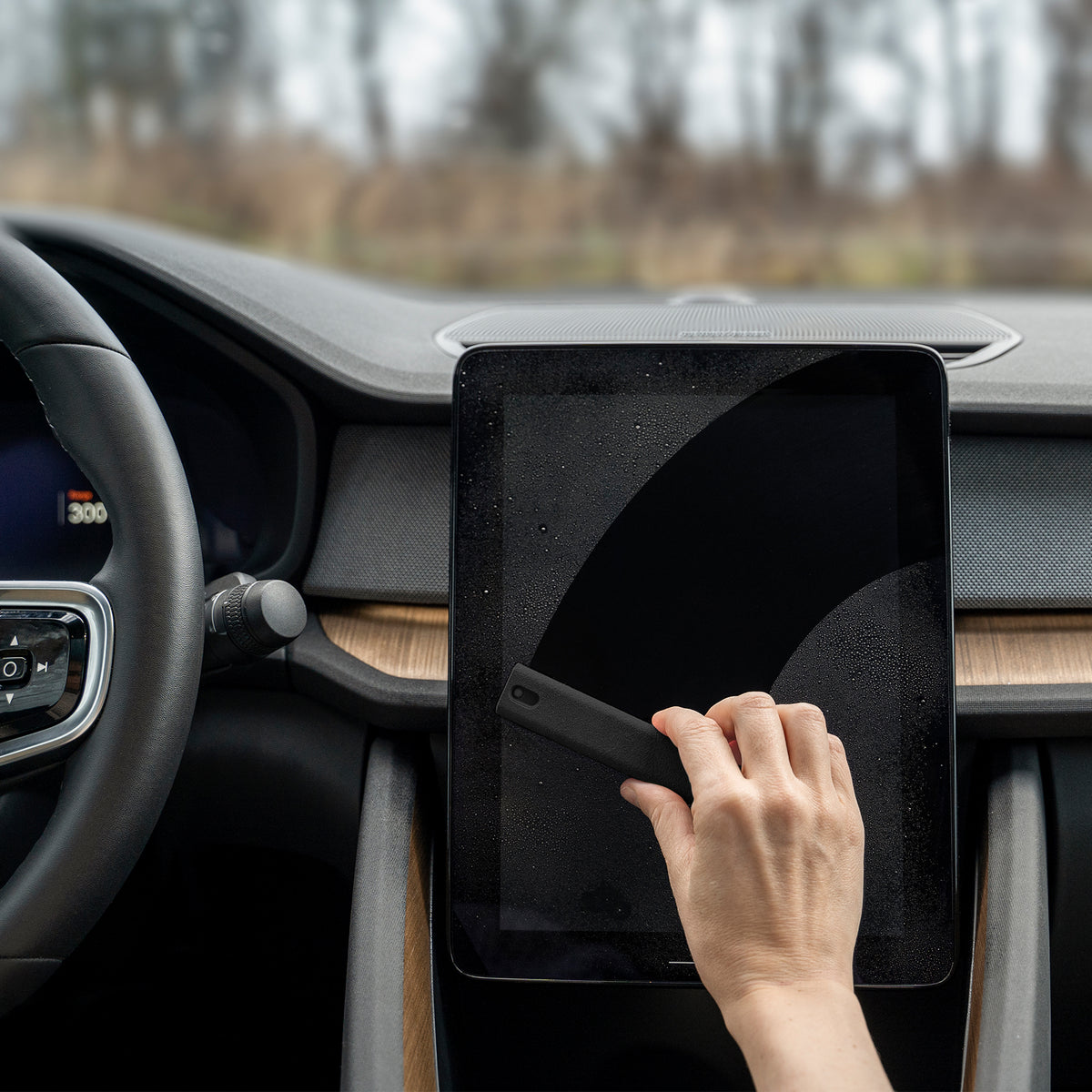 Person using a screen cleaner on the screen inside a vehicle