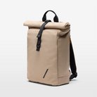 Side view of a Volvo backpack against a white background. Visible is the taupe colour, the black handle at the top, the roll-top with magnetic closure, adjustable straps and the Volvo Diagonal logo.