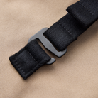 Detail view of Volvo Backpack. We see the taupe colour of the water-repellent coating, the robust material, and the end of one of the adjustable black straps. 