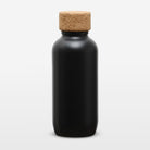 A matte black bottle with a natural cork stopper, centered on a clean white background.
